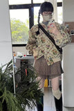 Person taking a mirror selfie wearing a floral jacket and plaid skirt indoors.
