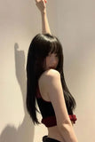 Person with long black hair against a plain wall
