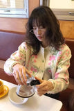 Woman in a floral sweater using a coffee filter in a kitchen setting
