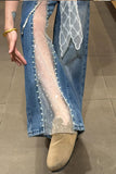 Person wearing sheer white stockings with blue jeans and beige shoes on a tiled floor.