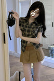 Woman taking a mirror selfie wearing a plaid shirt and beige skirt.