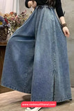 Person wearing a long blue denim skirt with a blurred background