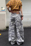 Person wearing a plaid shirt and camouflage pants standing in front of a closed shutter.