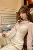 Woman in a white lace dress sitting on a couch with a blurred background
