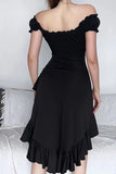 A woman wearing a black off-the-shoulder midi dress with a ruffled neckline, ruched waist, and layered ruffle hem, shown from the back in a bedroom setting.