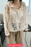 Person wearing a beige floral lace jacket and pants in an indoor setting.