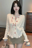 Woman wearing a cream-colored cardigan with red buttons in an indoor setting