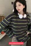 Person wearing a striped sweater with headphones around their neck, standing indoors.