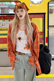Person wearing an orange plaid shirt and white floral top at a bus stop.