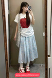Person taking a mirror selfie wearing a white t-shirt with a red top, light blue floral skirt, and red sneakers.