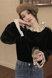 Woman wearing a black top with lace details and a brown beret, holding a glass.