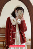Person wearing a red cardigan with decorative buttons in front of a mirror, taking a selfie.