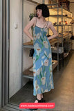 Woman wearing a floral dress in an indoor setting with shelves and decor.