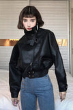Person wearing a black leather jacket and blue jeans indoors.