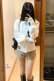 Person wearing a white shirt and beige shorts in front of a mirror.