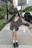 Person wearing a striped shirt and cap on a city street.