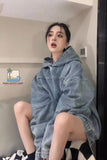 Person wearing a denim hoodie sitting on a chair in a room.