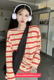 Person wearing a red and white striped sweater with headphones indoors.