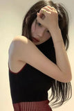Woman with long dark hair wearing a black top against a neutral background
