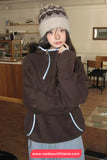 Person wearing a brown fleece jacket and patterned hat indoors, with a visible website URL at the bottom.