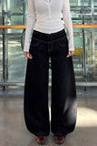 Person wearing a white long-sleeve shirt and black wide-leg jeans in an indoor setting.
