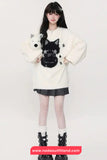 Person wearing a white sweater with black cat design and a black skirt on a white background.