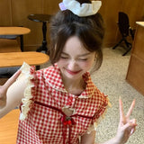 Person wearing a red and white checkered dress with ruffles, posing indoors.