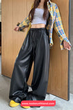 Person wearing a yellow plaid shirt, white crop top, and black high-waisted pants against a wooden panel background.