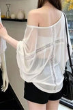 A woman shown from the back wearing a sheer white off-the-shoulder blouse with lace trim and black shorts in an indoor setting.