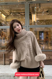 Woman wearing a beige sweater with fur trim in an indoor setting.