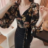 Person wearing a floral blouse and black skirt in an indoor setting