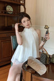 Woman in a white dress sitting in an elegant room with vintage decor