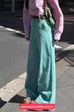 Person wearing teal wide-leg pants and a pink shirt on a street.