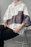Person wearing a white hoodie with a colorful pattern on a gray background