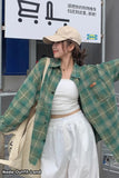 Woman wearing a green plaid jacket and white outfit in front of an IKEA store.