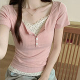 Person wearing a pink ribbed top over a white lace top, sitting indoors.