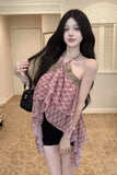 Woman wearing a pink plaid dress with a black handbag indoors.