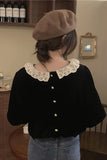 Person wearing a black blouse with a white lace collar and a brown beret in an indoor setting.