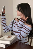 Person wearing a striped sweater sitting at a table with books