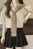 Person wearing a striped shirt, black skirt, and beige scarf indoors.