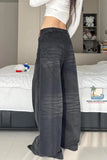 Person wearing wide-leg jeans in a bedroom setting with a bed and shelves in the background.