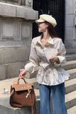 Woman in a white shirt and blue jeans holding a brown leather bag on stone steps.