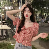 Woman wearing a red and white checkered blouse in an outdoor setting