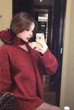 Person wearing a red sweater taking a mirror selfie.