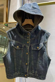Denim vest with hood on a hanger against a light-colored wall.