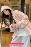 Person wearing a pink hooded coat holding a drink in an indoor setting