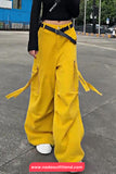 Person wearing yellow cargo pants with a black belt on a street.