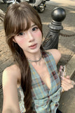Woman in plaid dress holding a phone on a street