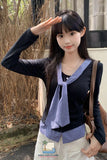 Person wearing a black sweater with a blue checkered scarf, standing outdoors.