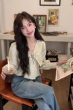 Woman sitting at a table with a drink and a painting in a cozy room.